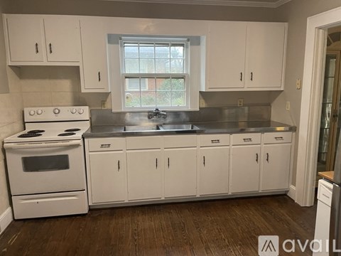 A kitchen with white cabinets and a stove top oven.
