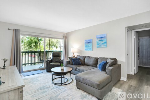 A living room with a grey couch, a black chair, and a small table.