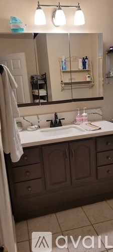 A bathroom with a brown vanity and a white sink.
