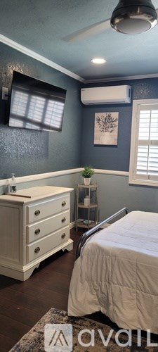 A bedroom with a bed, dresser, and window.