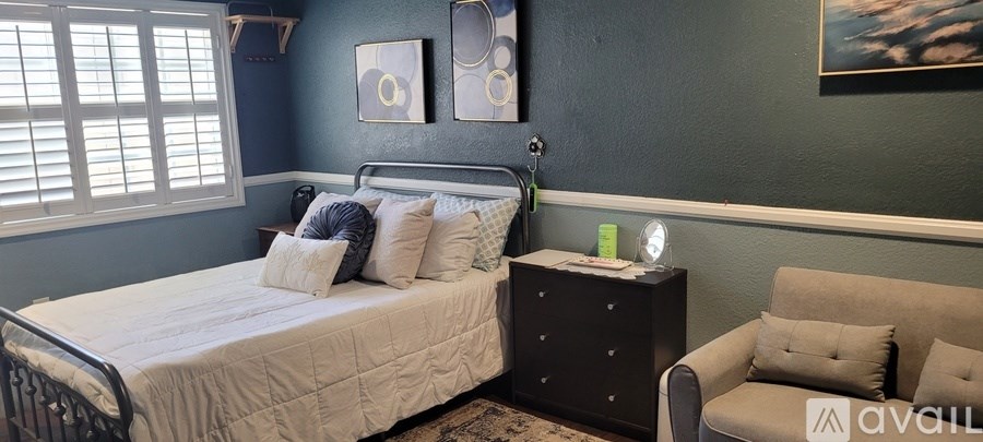 A bedroom with a bed, a nightstand, and a chair.