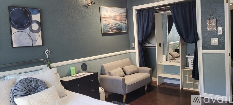 A bedroom with a bed, nightstand, chair, and a painting on the wall.