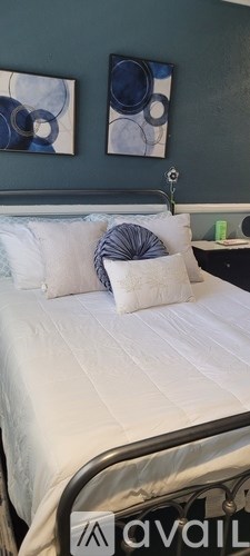 A bed with white sheets and a blue pillow is in the foreground.