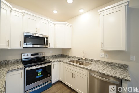 A kitchen with white cabinets and a granite countertop.