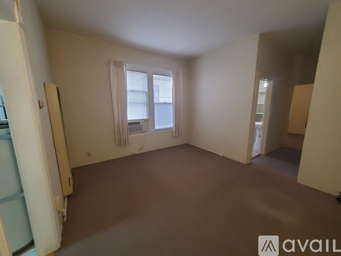 A room with a window and a door is available for rent.