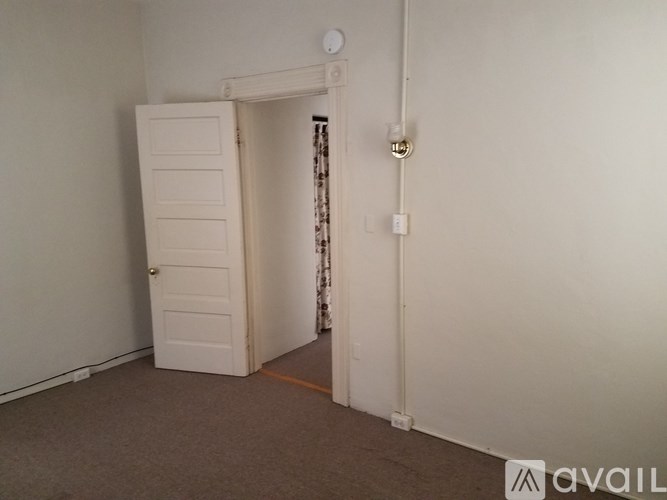 A room with a white door and a carpeted floor.