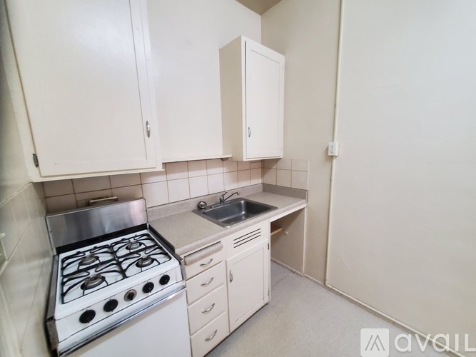 A kitchen with a stove, sink, and cabinets.
