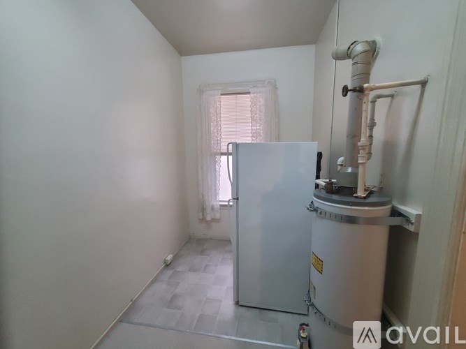 A room with a white refrigerator and a water heater.