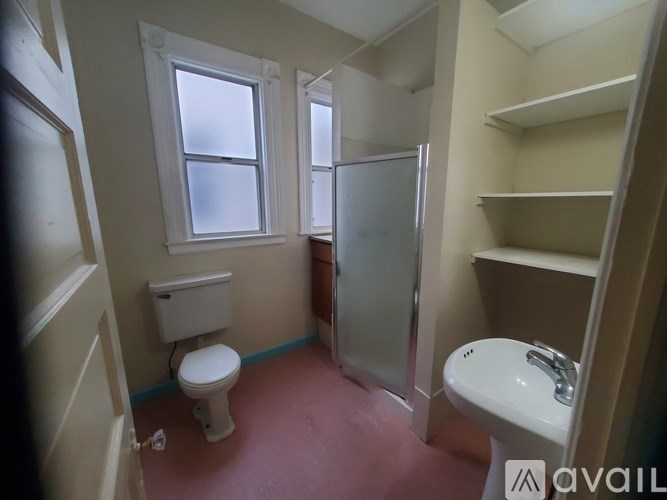 A bathroom with a toilet, sink, and a window.