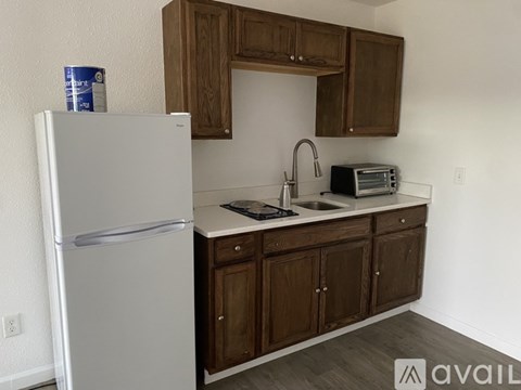 A kitchen with a white refrigerator, wooden cabinets, and a white countertop.