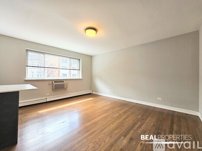 A room with wooden flooring and a window on the wall.