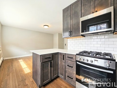 A kitchen with dark wood cabinets and a stove top oven.
