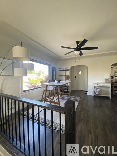 A living room with a dining table and chairs, a ceiling fan, and a balcony with a railing.