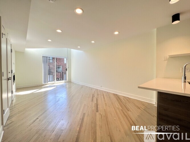 A spacious room with a kitchen island and wooden flooring.