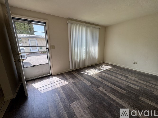 A room with wooden flooring and a sliding glass door leading to a balcony.