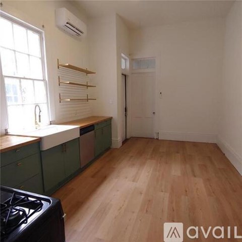 A kitchen with green cabinets and a black stove top.