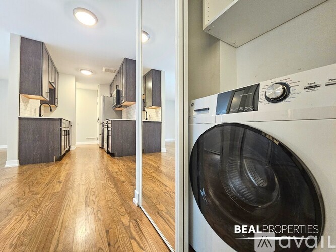 A BEALPROPERTIES sign is on a wall in a room with a washer and dryer.
