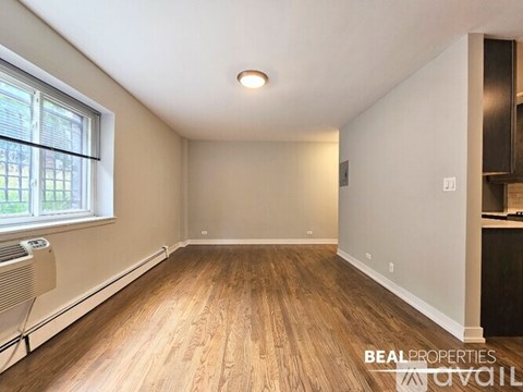 A spacious room with wooden floors and a large window.