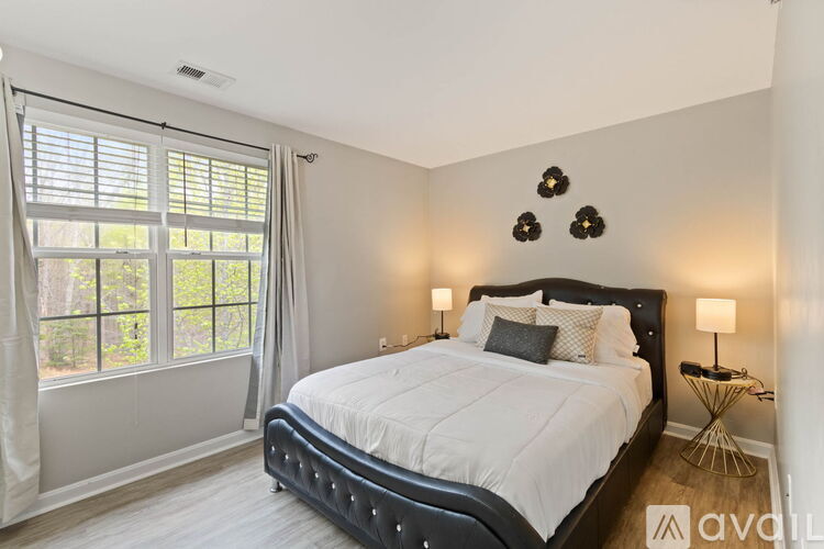 A bedroom with a large bed and a window with blinds.