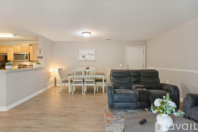 A living room with a grey couch and a white table with a vase of flowers on it.