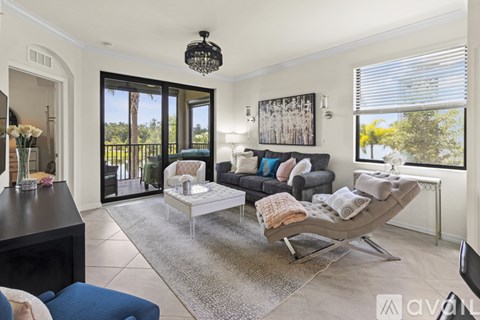 A living room with a black sofa, a grey chaise lounge, a black coffee table, and a large painting on the wall.