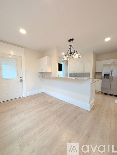 A kitchen with a white counter and wooden flooring.