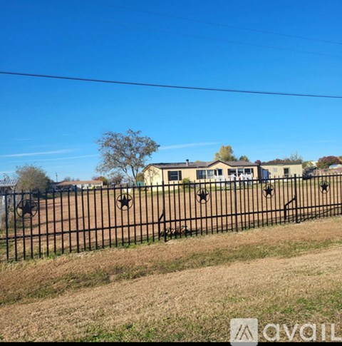 A black fence with a tree and a building in the background.