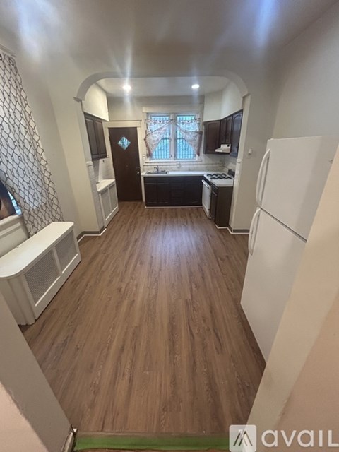 A kitchen with wooden floors and a white refrigerator.