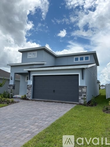 A modern house with a large garage door is for sale.