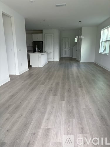 A spacious living room with wooden flooring and white walls.
