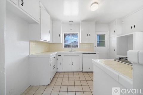 A kitchen with white cabinets and a tiled floor.
