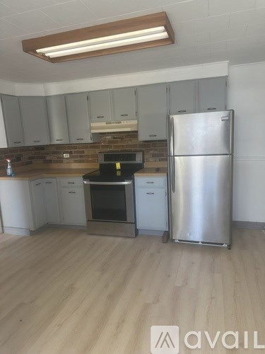 A kitchen with a stainless steel refrigerator and wooden flooring.