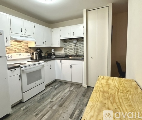 A kitchen with white cabinets and a wooden floor.
