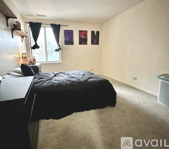 A bedroom with a bed, desk, and window with curtains.