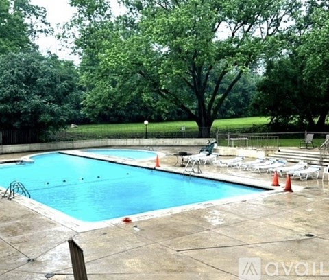 A pool surrounded by trees and chairs.