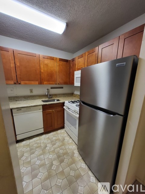 A kitchen with a stainless steel refrigerator and a tiled floor.