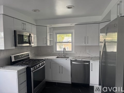 A kitchen with white cabinets and black appliances.