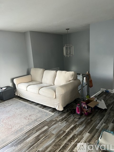 A living room with a white couch and a rug on the floor.