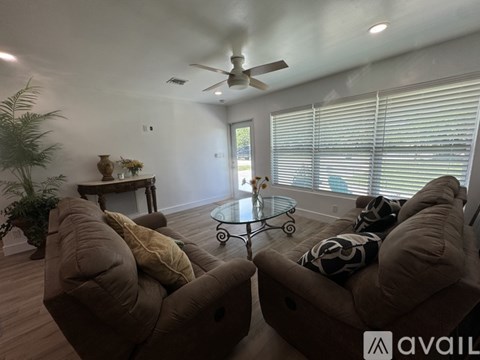 A living room with two brown couches and a glass coffee table.