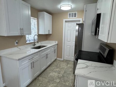 A kitchen with white cabinets and a marble countertop.