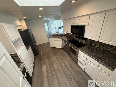 A kitchen with white cabinets and a black refrigerator.