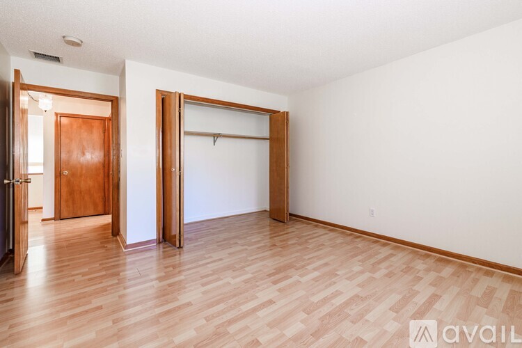 A room with wooden floors and white walls has two doors and a large empty space.