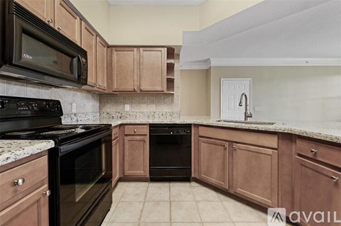 A kitchen with brown cabinets and black appliances.