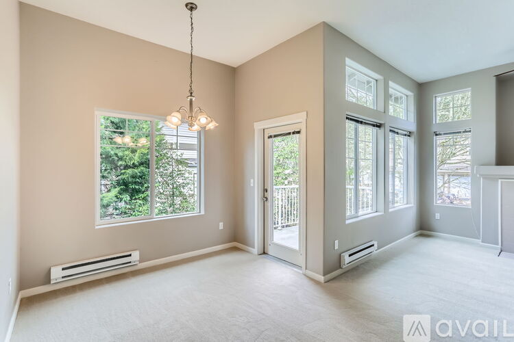 A spacious room with a chandelier, large windows, and a door leading to a balcony.