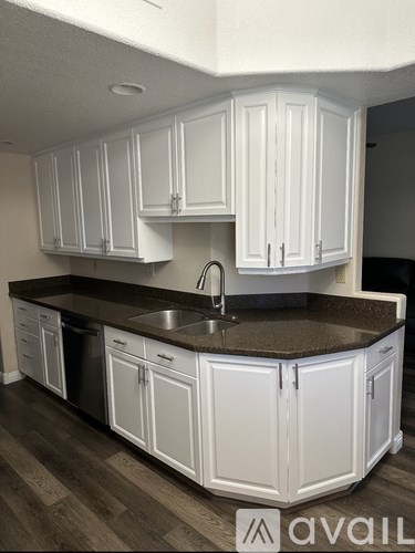 A kitchen with white cabinets and a dark countertop.