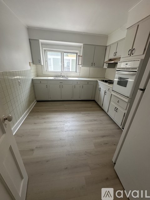 A kitchen with white cabinets and a white fridge.