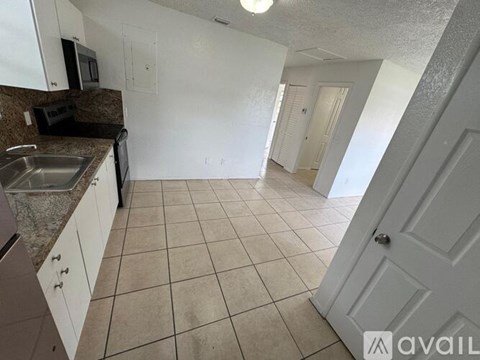 A kitchen with white cabinets and a black microwave.