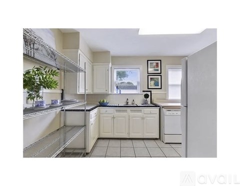 A kitchen with white cabinets and a window.