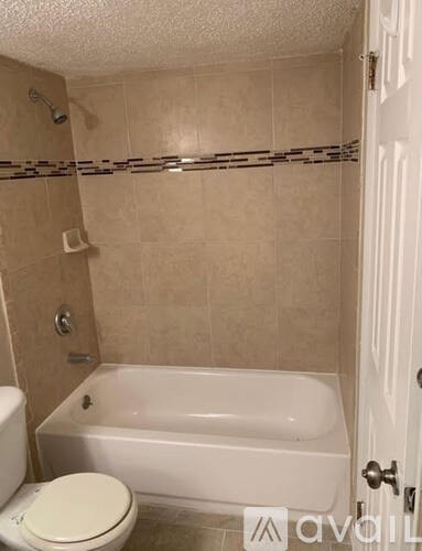 A white toilet sits next to a bathtub in a bathroom.