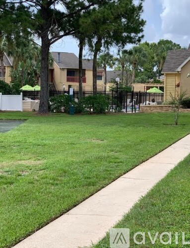 A grassy area in front of a house with a tree and a fence.